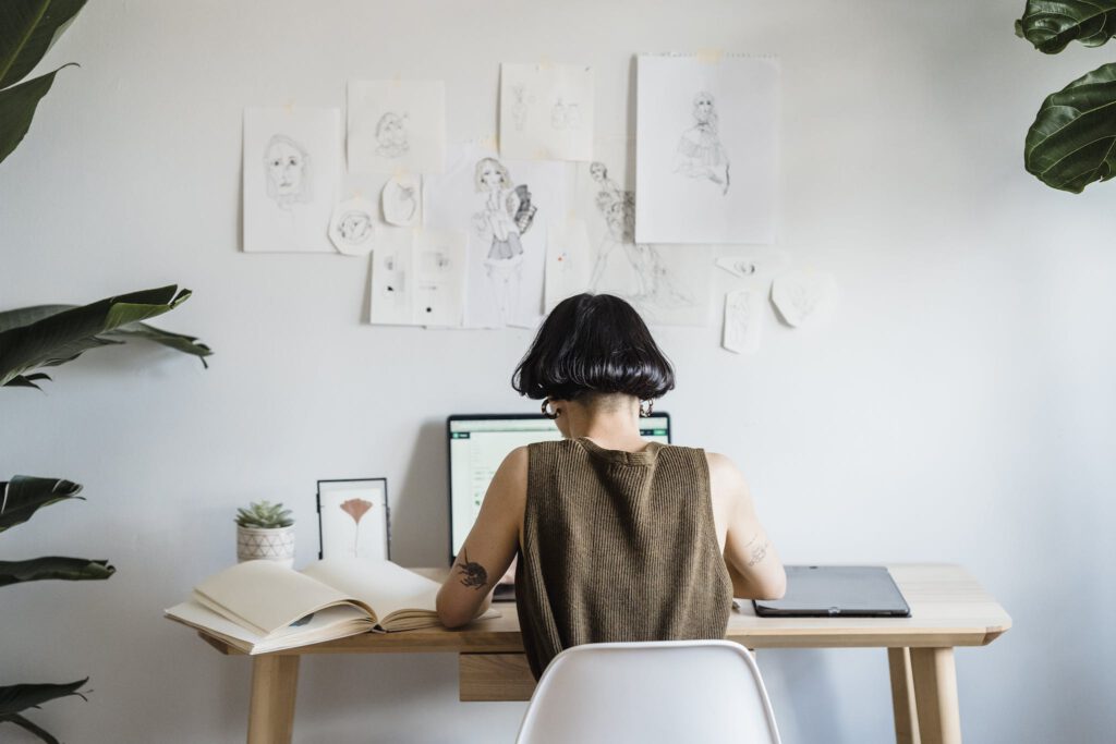 Focused female artist working on laptop in light room